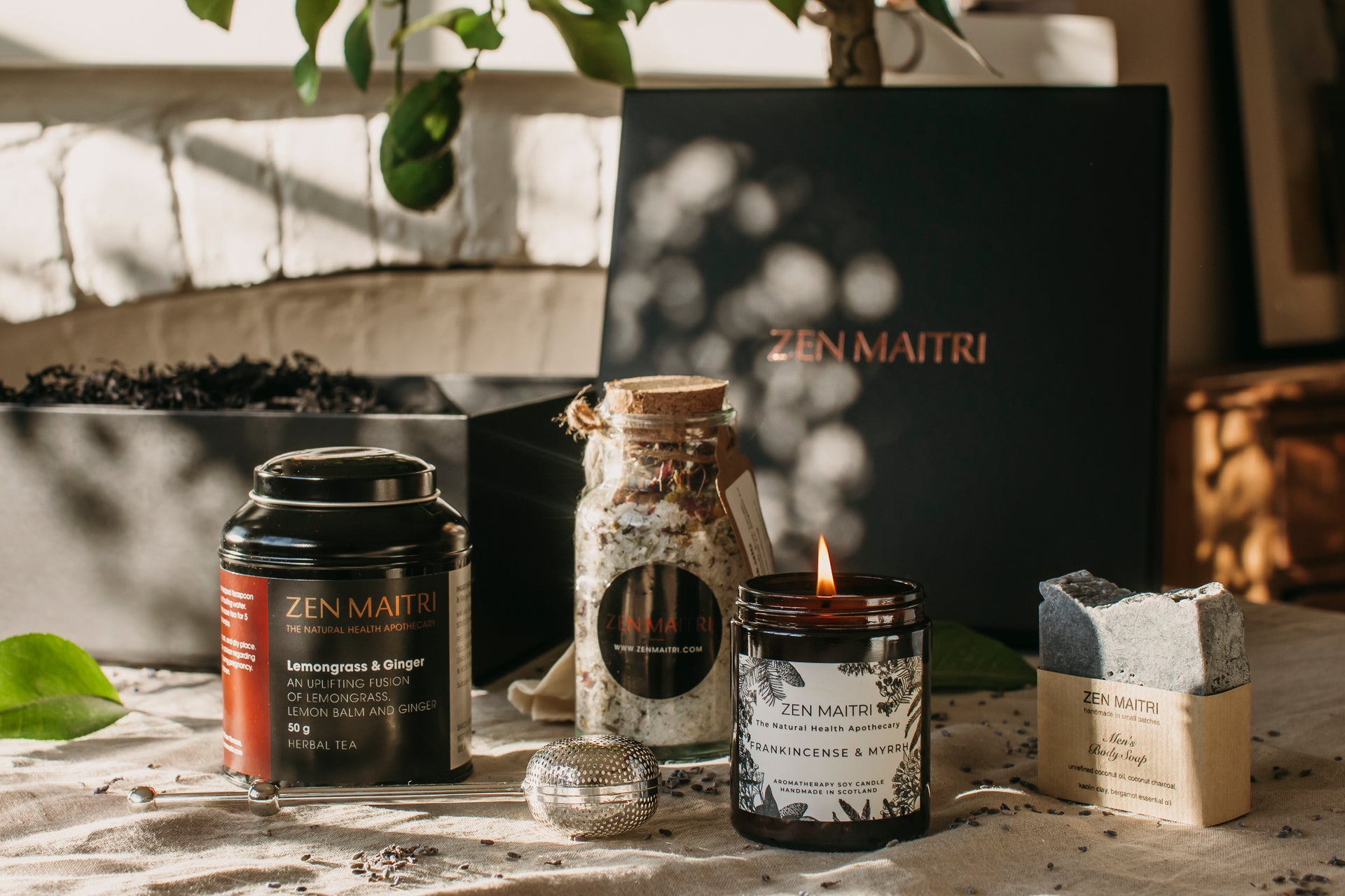 Zen Maitri products including candles and tea on a table with a blurred background