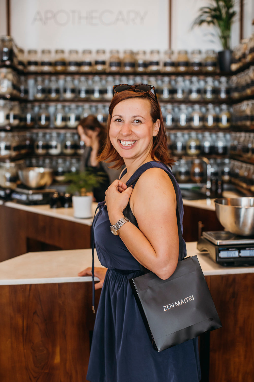Woman holding a black bag with 'ZENMAIRTI' branding in a store setting.