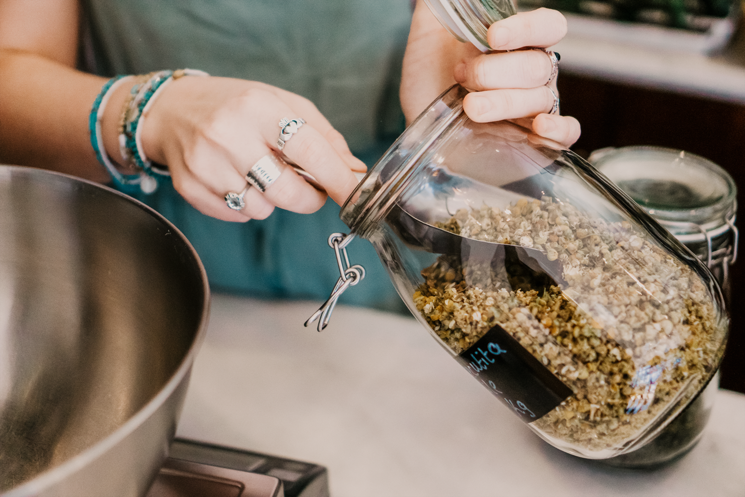 Person measuring ingredients into a jar on a kitchen counter